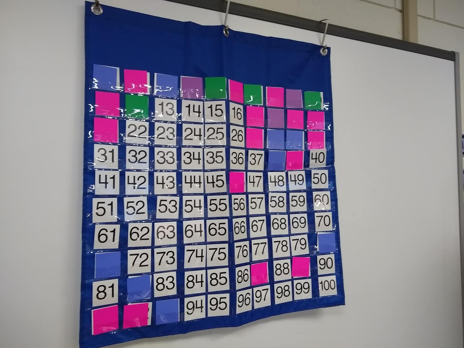 hundred chart with some numbers covered with squares of colored paper for yearly number challenge. 