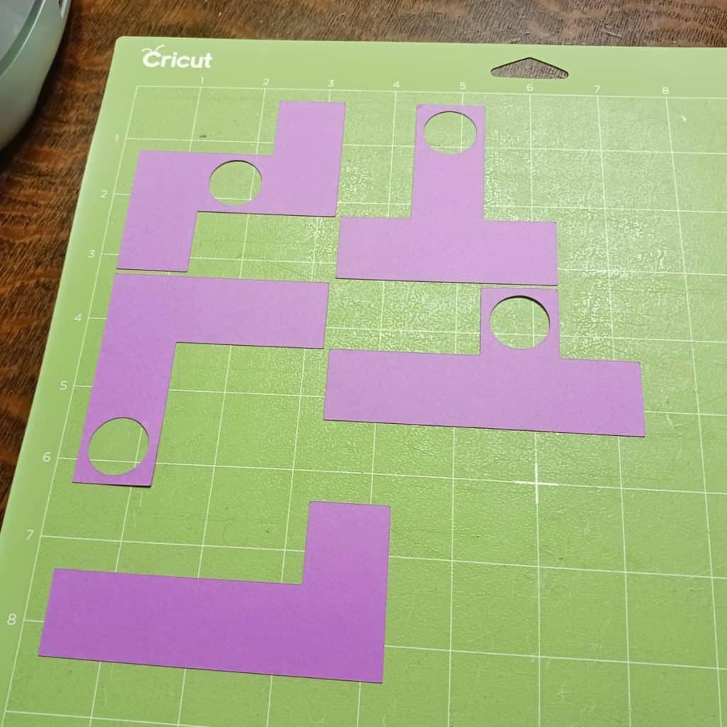 page of pentomino pieces with holes in them on cricut cutting mat. 