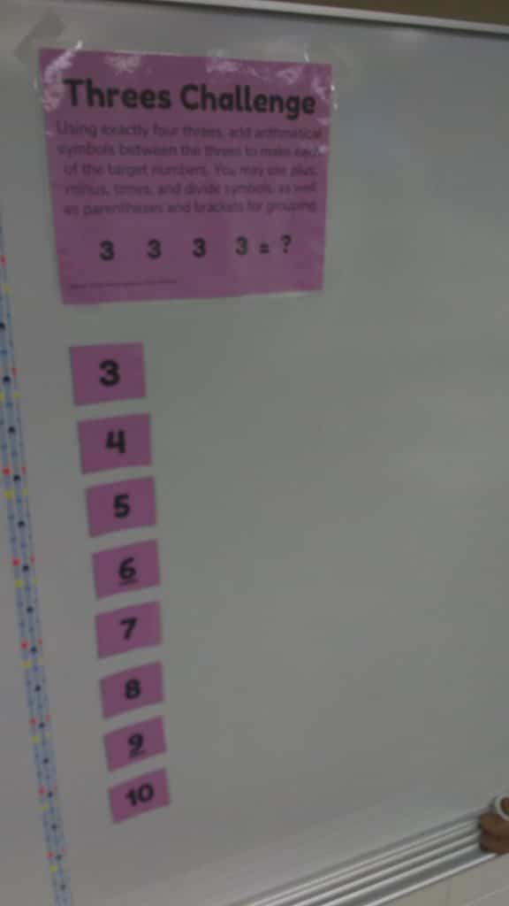 threes challenge hanging on dry erase board. 